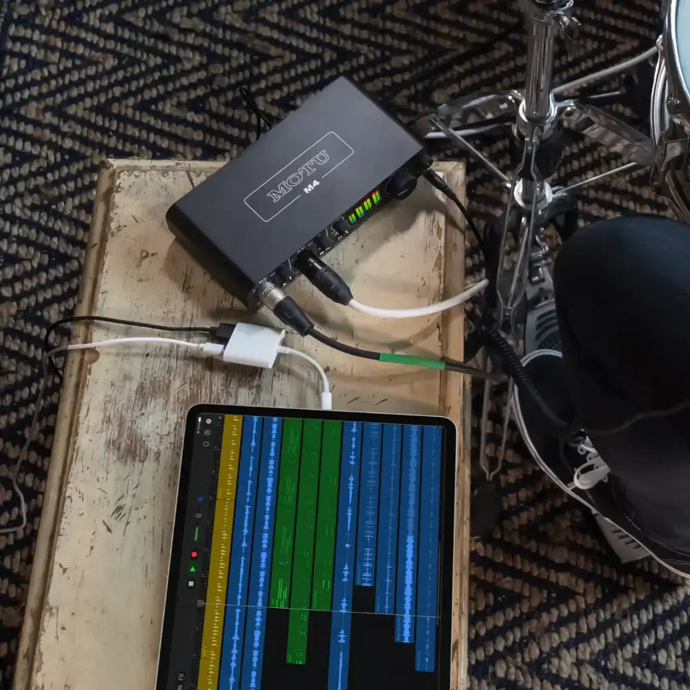 MOTU M4 USB-C audio interface connected to a tablet, showcasing audio tracks and vibrant recording levels.